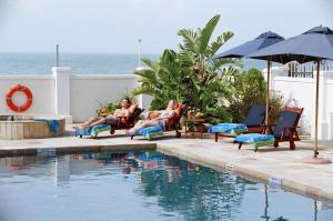eine Gruppe von Personen, die an einem Pool auf Stühlen sitzen in der Unterkunft The Beach Hotel in Port Elizabeth