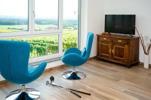 a room with two blue chairs and a television at Ferienhaus im Weingarten in Klöch