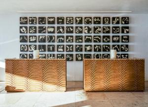 Habitación con 2 mesas de madera frente a una pared con obras de arte. en Viceroy Los Cabos, en San José del Cabo