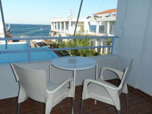 een tafel en 2 stoelen op een balkon met uitzicht op de oceaan bij Seafront Studios and Apartments in Chios