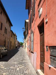 eine Kopfsteinpflasterstraße in einer Gasse mit einem roten Gebäude in der Unterkunft La Dimora di Cesare in Fano
