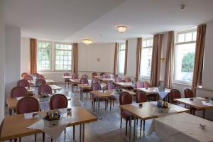 a dining room with tables and chairs and windows at Parkhotel Altenburg in Altenburg