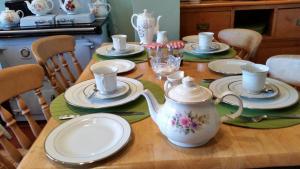 uma mesa de madeira com pratos e um bule de chá em Kingsway Bed & Breakfast em Broxbourne