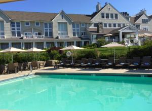 a pool with chairs and umbrellas in front of a resort at Inn By the Sea in Cape Elizabeth