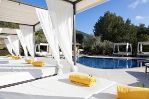 a row of tables with yellow pillows on them next to a pool at Finca Albellons in Binibona