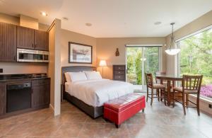 a bedroom with a bed and a table and a kitchen at Inn the Estuary in Nanoose Bay