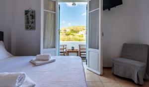 a bedroom with a bed and a chair and a window at Iliopoulou Studios in Pollonia