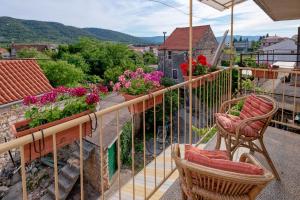 a balcony with chairs and flowers on a house at Guesthouse Wish in Stari Grad