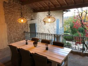 einen Holztisch mit Stühlen und Lampen auf dem Balkon in der Unterkunft Mas des Poutres - Gîte Rose in Charmes-sur-lʼHerbasse