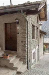 un edificio de piedra con una puerta de madera y escaleras en La baita di Brusson, en Brusson