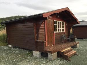 Cabaña pequeña con ventana y silla en Harran Camping, en Grong