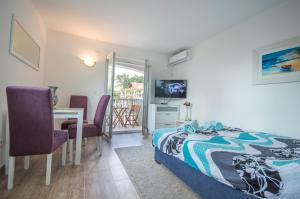 a bedroom with a bed and a table and a television at Queen Teuta - Sea View - Private Parking & Garden - BBQ Grill in Risan