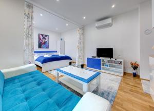 Una sala de estar con un sofá azul y una cama. en Apartments Best, en Mostar