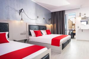 two beds in a hotel room with red and white at House Katerina Mediterranean in Sarti