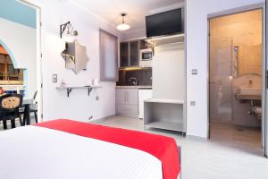 a bedroom with a white bed and a kitchen at House Katerina Mediterranean in Sarti