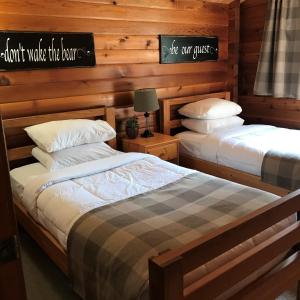 two twin beds in a room with wooden walls at Cloverleaf Cottages in Oxtongue Lake