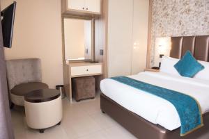 ein Hotelzimmer mit einem großen Bett und einem Stuhl in der Unterkunft Britannia Hotel in Durban
