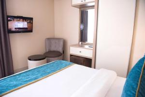 ein Schlafzimmer mit einem Bett, einem Spiegel und einem Stuhl in der Unterkunft Britannia Hotel in Durban