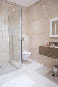 a bathroom with a shower and a toilet and a sink at Britannia Hotel in Durban