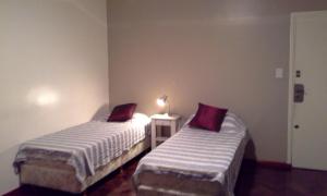2 camas en una habitación pequeña con una lámpara en una mesa en Estudio en Buenos Aires