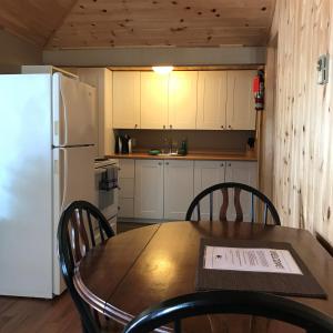 cocina con mesa, sillas y nevera en Cloverleaf Cottages, en Oxtongue Lake