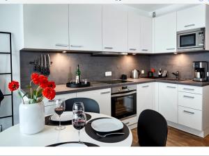 uma cozinha com armários brancos e uma mesa com flores vermelhas em Grünstrand em Travemünde