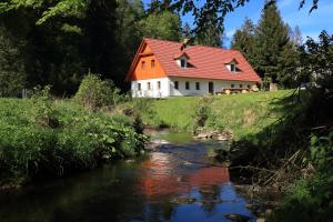 una casa con techo rojo junto a un río en Chalupa U první skály, en Chřibská