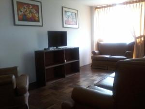 a living room with a couch and a television at Royal Sweet Dreams Airport B&B in Lima