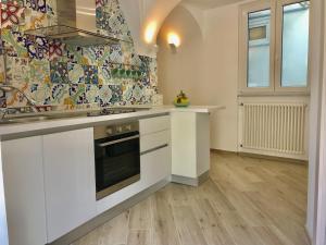 una cucina con armadietti bianchi e una parete piastrellata di Trifoglio Apartment a Maiori