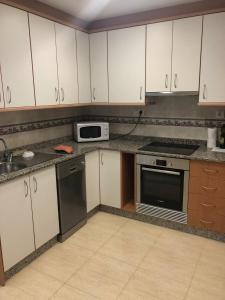 eine Küche mit weißen Schränken und Geräten aus Edelstahl in der Unterkunft Piso Soballa, Centro y Playa in Santa Pola