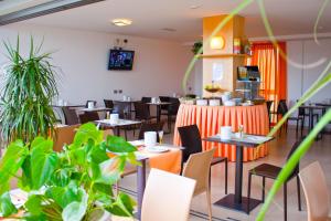 un restaurante con mesas, sillas y plantas en Hotel Pasha, en Lignano Sabbiadoro