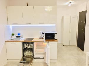 uma cozinha com armários brancos e um micro-ondas em Andersena 190 B - 12 piętro - 10 min CMKP - 5 min Metro - 15 min Centrum em Varsóvia
