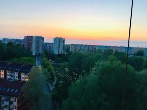 een zonsondergang boven een stad met hoge gebouwen en bomen bij Andersena 190 B - 12 piętro - 10 min CMKP - 5 min Metro - 15 min Centrum in Warschau