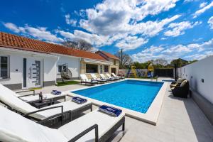 une piscine avec des chaises longues et une maison dans l'établissement Villa Mare - with HEATED POOL, à Zadar