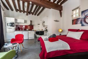 a bedroom with a red bed and a kitchen at Le Saint-Aignan, Nuits-chartraines, Parking privé a quelques minutes, 3 étoiles in Chartres