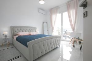 a white bedroom with a bed and a large window at PORTO AZZURO SITHONIA GREECE in Neos Marmaras