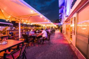 people sitting at tables outside a restaurant at night at Majestic City Suites & Beach Hotel in Willemstad