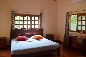 a bedroom with a bed and a desk and two windows at Los Cocos, Chinandega in Chinandega