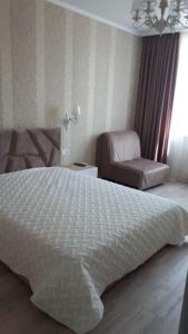 a bedroom with a white bed and a chair at Apartments Lutsdorf in Odesa