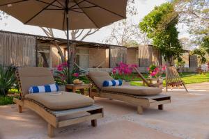 a patio with two lounge chairs and an umbrella at Hotel Casa de Campo Conkal Merida in Conkal
