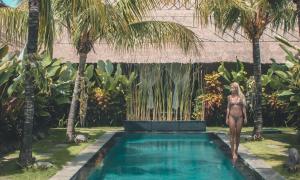a woman in a bikini standing next to a swimming pool at Karmagali Boutique Suites - adults only & Private Villas - families in Sanur