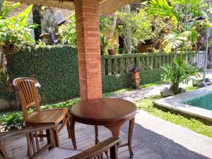 una mesa y sillas en un patio junto a la piscina en Ubud Lestari Bungalows en Ubud