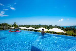 a man standing in a swimming pool with umbrellas at Babylon Sky Garden - Long Term Holiday Rentals in Rawai Beach