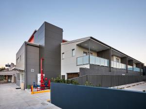 un edificio gris con una valla delante en East Maitland Executive Apartments, en Maitland