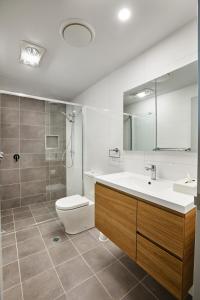 a bathroom with a sink and a toilet and a mirror at East Maitland Executive Apartments in Maitland