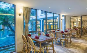 a dining room with tables and chairs and windows at Salmalia Boutique Hotel & Spa in Danang