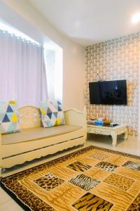 a living room with a couch and a television at Luxury Furnished 2BR Grand Kamala Lagoon Apartment By Travelio in Pulosirih