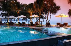 einen Pool mit Liegestühlen und Sonnenschirmen am Strand in der Unterkunft Impiana Beach Front Resort Patong, Phuket in Patong Beach