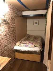 a bed in a small room with a brick wall at Shabby House in Sapporo