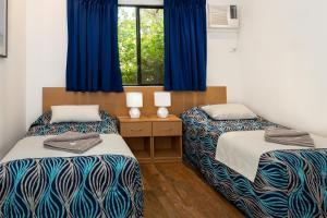 two beds in a room with blue curtains at Broome Beach Resort - Cable Beach, Broome in Broome